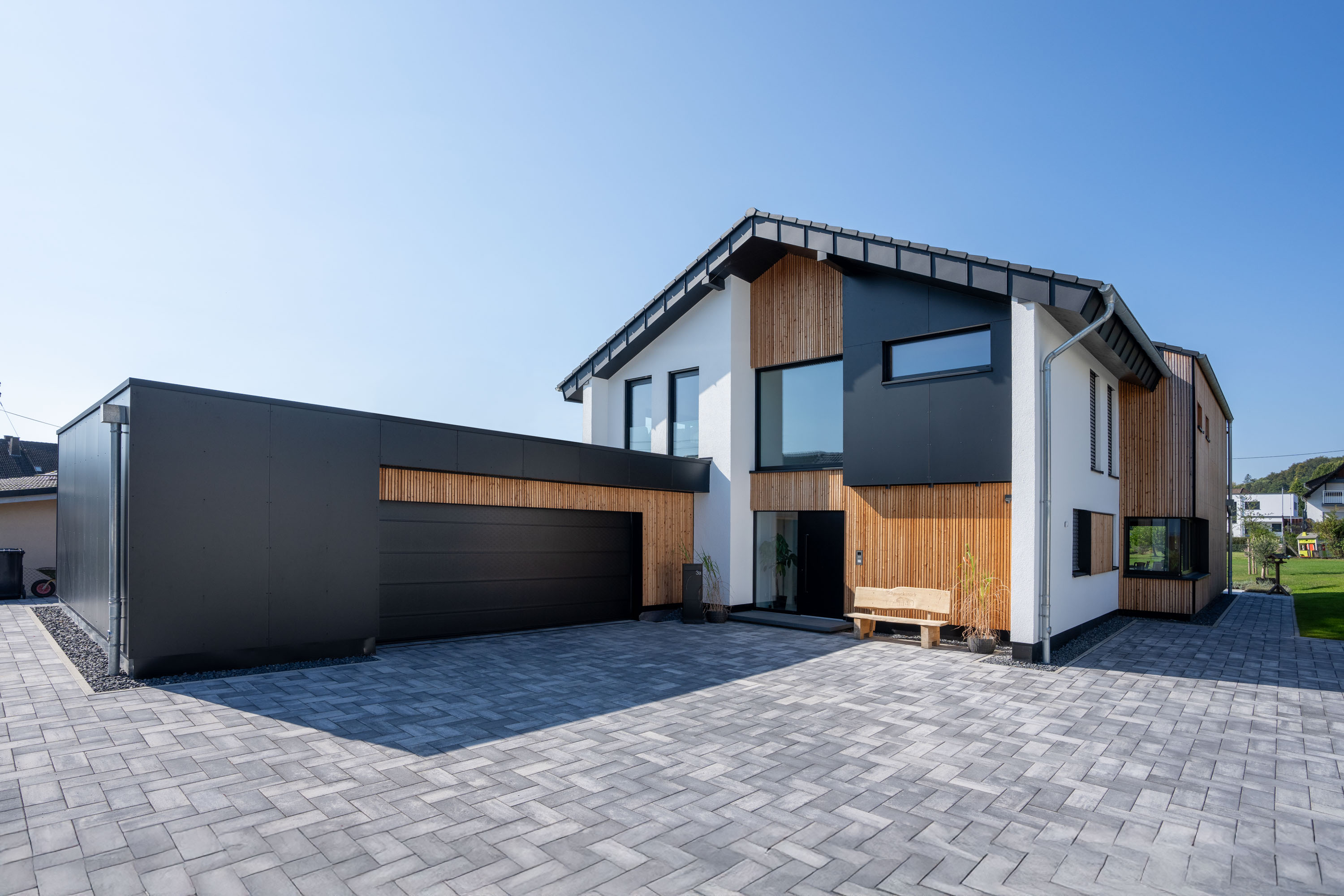 Moderne Holz-Putz-Fassade mit kontrastreichem Satteldach und Flachdach-Garage